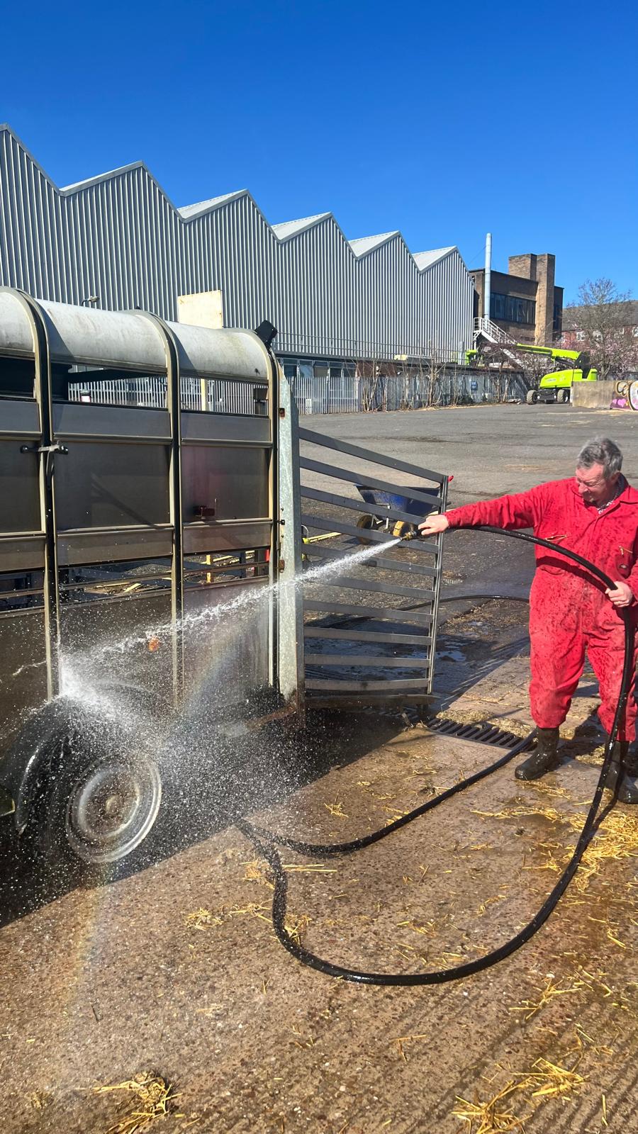 Wide shot of Steve hosing down the livestock trailer