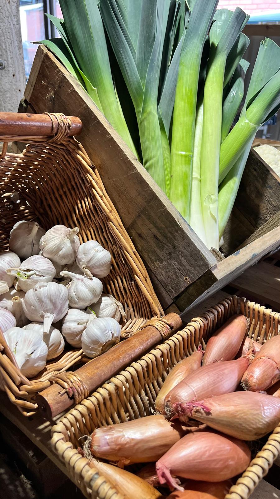 Garlic, leeks and shallots in baskets in the shop