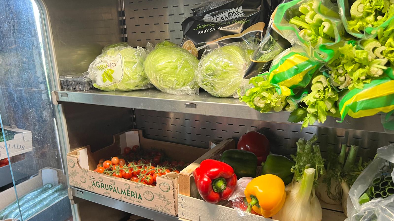 Shop fridge stocked with lettuce, peppers and tomatoes